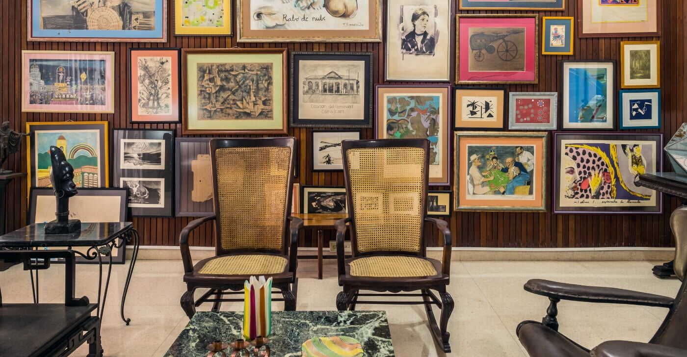Gallery wall with numerous framed paintings of various styles and ages