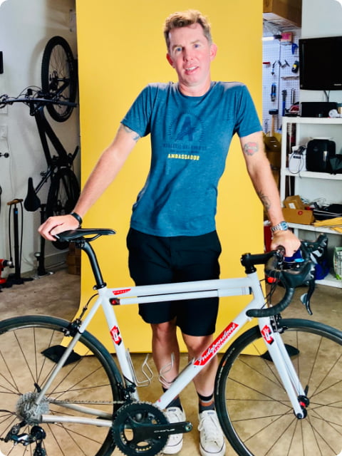 Cyclist standing posed behind his custom bike